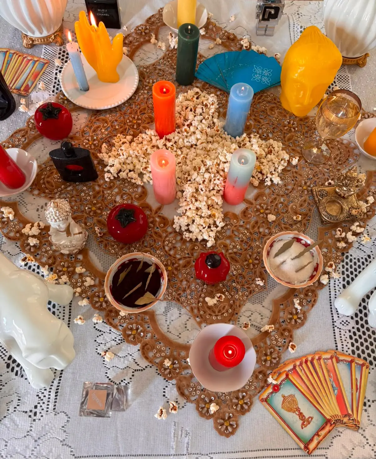 Mesa ritualística com velas coloridas, cartas de tarô e oferendas