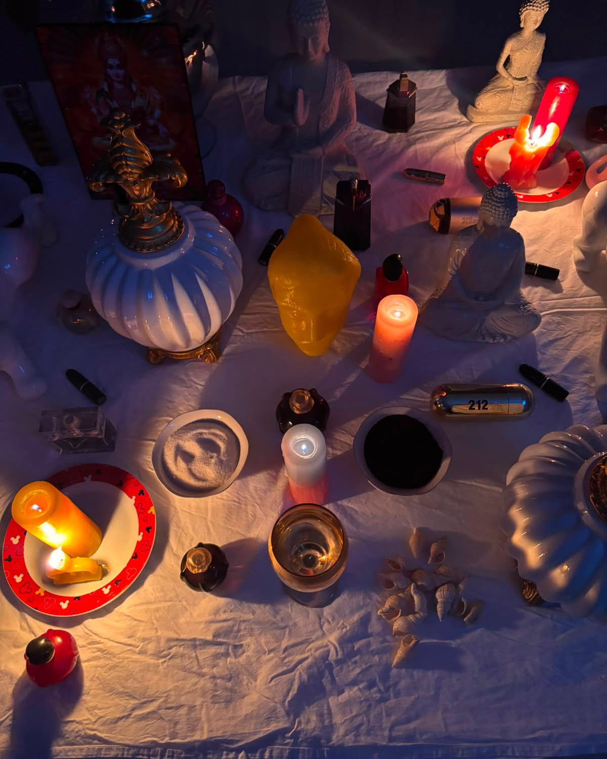 Ritual noturno com velas acesas, imagens sagradas e búzios