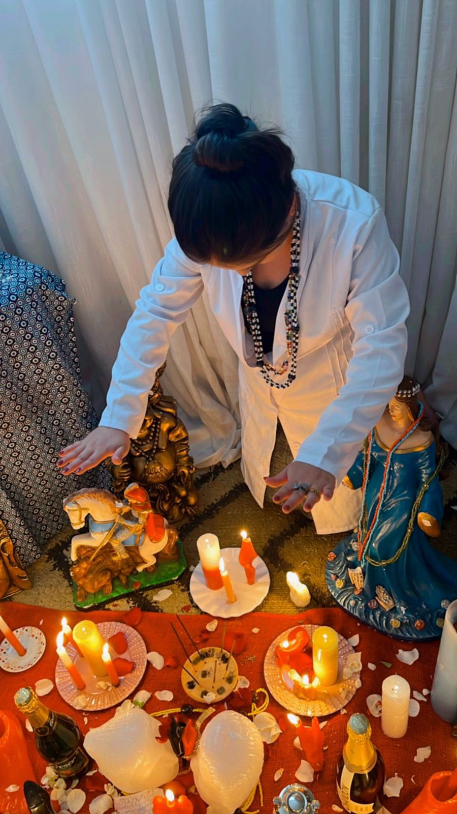Taróloga Isabella conduzindo um ritual com velas e imagens sagradas